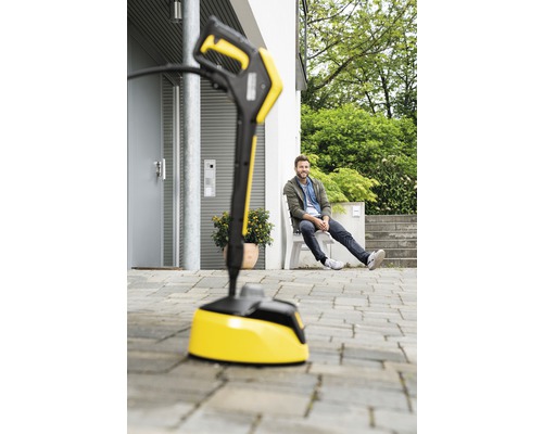 Gele terrasreiniger voor een huis met een zittende man