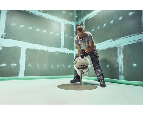 Man giet egalisatiemiddel op een vloer in een ruimte met geprepareerde wanden