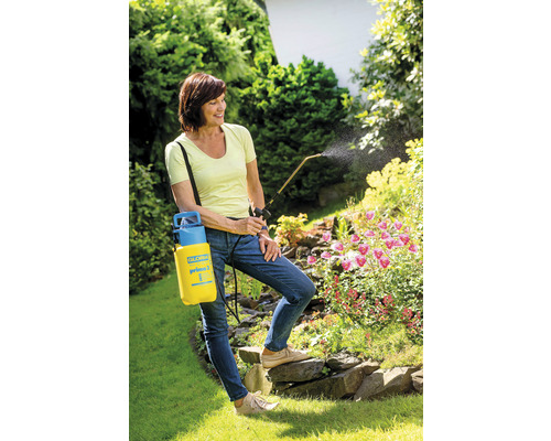 Vrouw gebruikt een gele tuinspuit voor plantverzorging in de tuin.