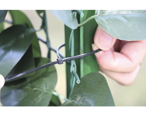 Gedetailleerde opname van de bevestiging van een kunsthaag met een kabelbinder.