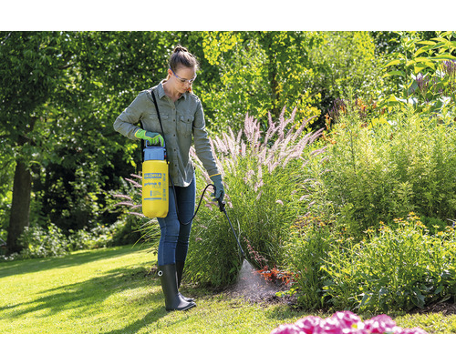 Vrouw gebruikt Gloria Prima 5 Plus drukspuit in de tuin voor plantenverzorging