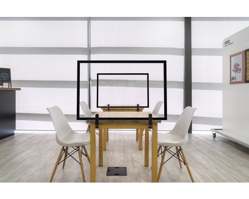 Tafels met transparante beschermende schermen en stoelen in een kantoor