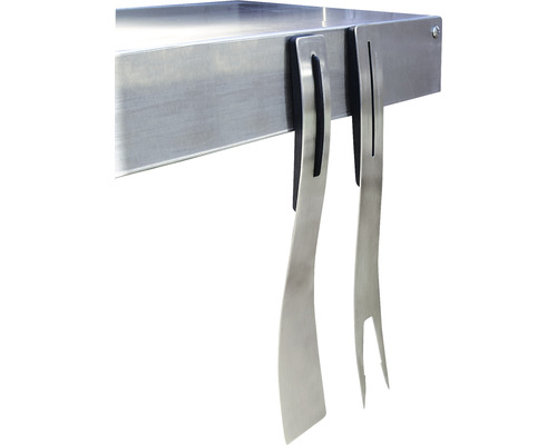 Barbecueaccessoires zoals een metalen spatel en vork hangen aan een barbecuetafel.