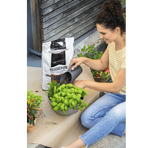 Vrouw vult een plantenbak met kruiden en Veggiepon groentegrond.