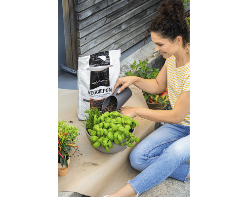 Vrouw vult een plantenbak met kruiden en Veggiepon groentegrond.