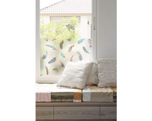 Raam met raamfolie en verenmotief, zitbank met kussens.