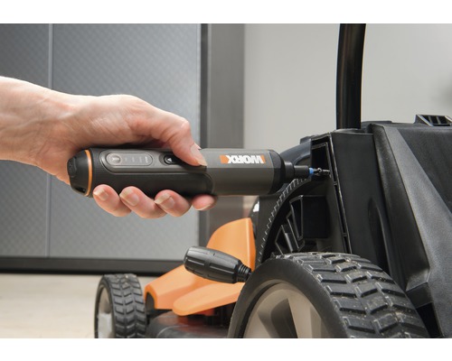 Een hand houdt een accuschroevendraaier vast die op een grasmaaier wordt gebruikt.