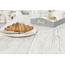Een croissant met mes op een bord en een dienblad op een houten tafel