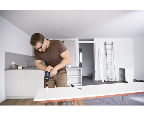 Man boort gat in werkstuk met gatzagen in lichte woning