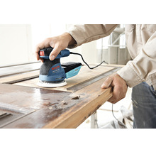 Een man gebruikt een Bosch excentrische schuurmachine om een houten deur te schuren.