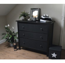 Slaapkamer met zwart dressoir met drie laden, spiegel en kamerplanten