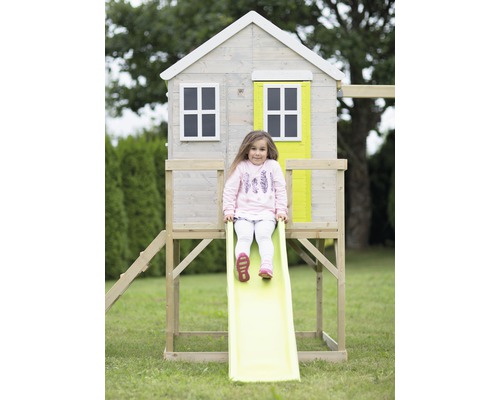 Meisje glijdt van een speelhuisglijbaan in de tuin