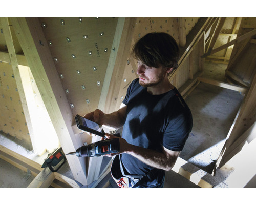 Man fotografeert met een mobiele telefoon een boormachine voor een houten dakspant