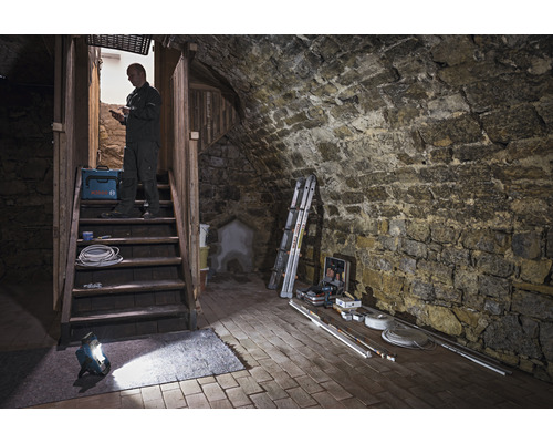 Kelderruimte met stenen trap, bouwlamp, gereedschapskist en vakman