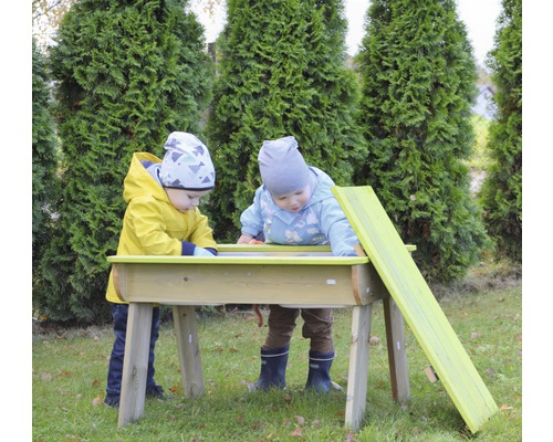 Twee kinderen spelen buiten aan een zandtafel met helling.