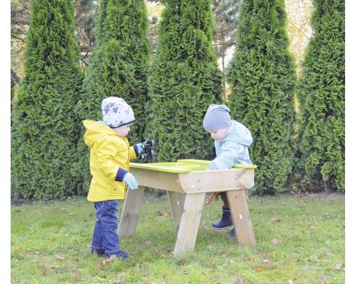 Twee kinderen spelen aan een zand- en watertafel in de tuin.