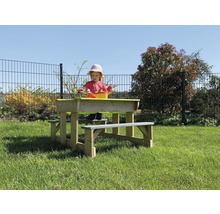Kind bij houten picknicktafel met zandbak in de tuin