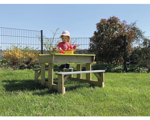 Kind bij houten picknicktafel met zandbak in de tuin