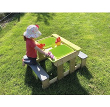 Kind speelt aan zand- en watertafel met zitbanken in de tuin.
