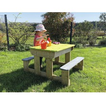 Kind speelt aan picknicktafel in de tuin. De houten tafel heeft banken en een groen tafelblad.