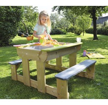 Kind speelt aan een zand- en watertafel met zitbanken in de tuin.