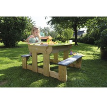 Kind speelt aan houten picknicktafel met zandbakfunctie in de tuin.