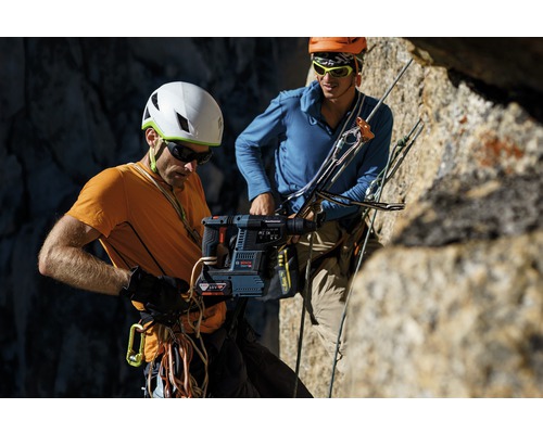 Twee bergbeklimmers in een rotswand, een met een accuboorhamer.