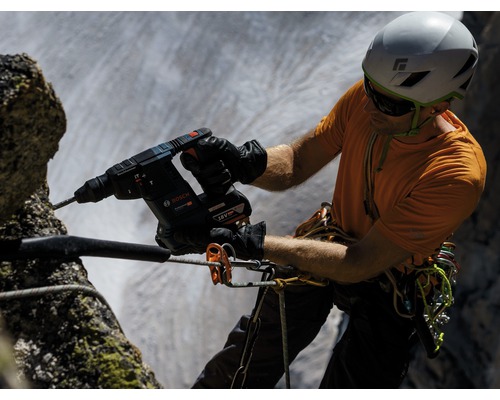 Een man boort met een accuboorhamer van Bosch in een rots.