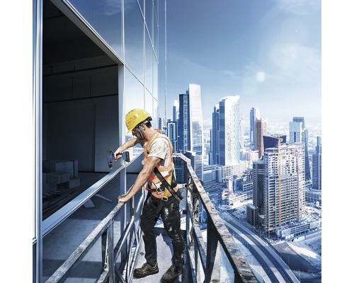 Een bouwvakker met veiligheidshelm en veiligheidsvest monteert ramen aan een gebouw op grote hoogte