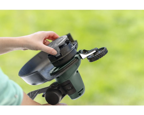 Een persoon vervangt de spoel van een grastrimmer.