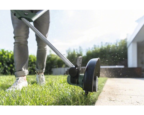 Een persoon snijdt gazonranden met een grastrimmer.