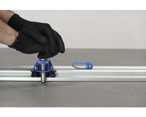 Tegelsnijder in gebruik met handschoenen op aluminium geleiderail