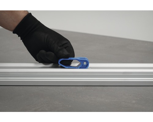 Een hand met beschermende handschoen bevestigt een blauwe schuif aan een aluminium rail.