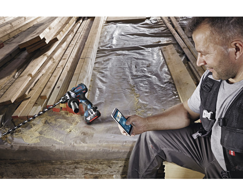 Accuboormachine met houtboor en vakman met smartphone