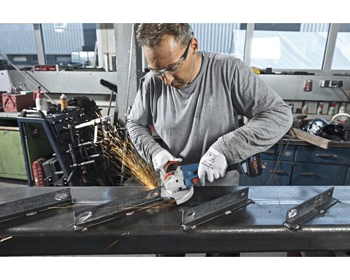 Een man draagt een veiligheidsbril en gebruikt een haakse slijper om metaal te slijpen, waarbij vonken ontstaan.