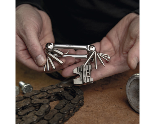 Multitool in handen met fietsketting op tafel