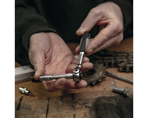 Close-up van een persoon die een dopsleutel gebruikt om een schroef aan te draaien.