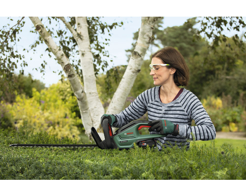 Vrouw snoeit heg met Bosch accuschaar