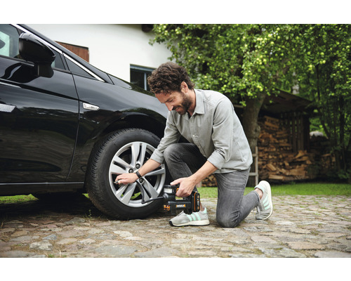 Man pompt autoband op met een draadloze compressor