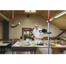 Man filmt een modeltrein met een camera op een statief en een werklamp.