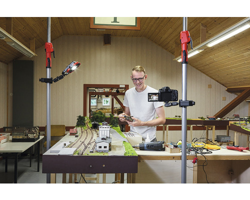 Man filmt een modeltrein met een camera op een statief en een werklamp.