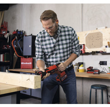 Man zaagt met een accusabelzaag een houten plank in een werkplaats.