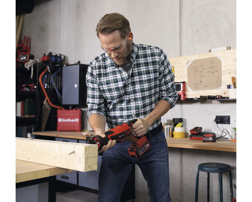 Man zaagt met een accusabelzaag een houten plank in een werkplaats.
