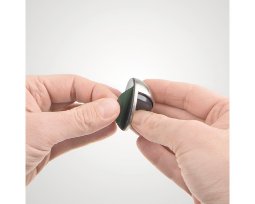 Een hand houdt een meubelglijder met vilten glijvlak vast.