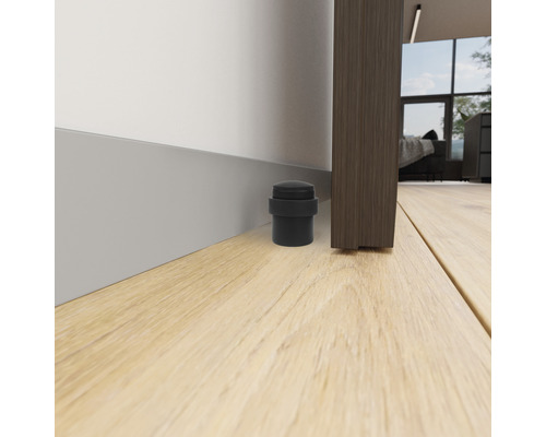 Rubberen deurstopper op de vloer naast een deur