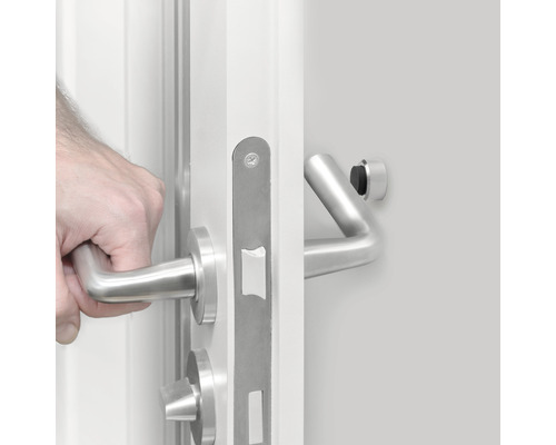 Hand opent witte deur met roestvrijstalen beslag