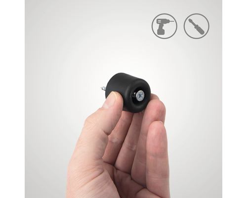 Een hand houdt een zwarte deurstopper vast voor montage met een schroef. Installatiesymbolen op de achtergrond.