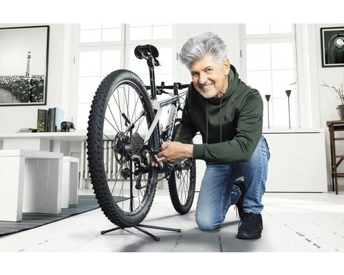 Man repareert een fiets in een lichte kamer.