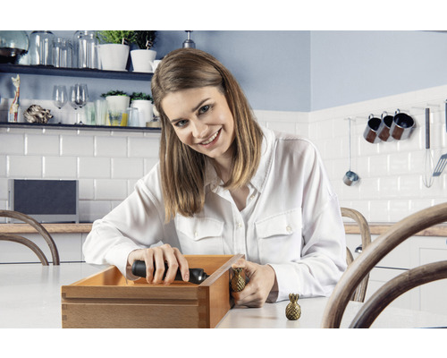 Vrouw monteert ladeknop in ananasvorm op houten lade in keuken