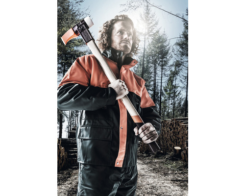 Een man in beschermende kleding houdt een kloofbijl in het bos vast.